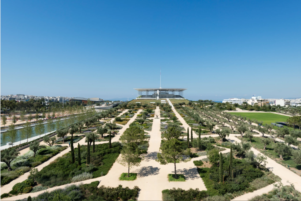 the SNFCC Park in a picture taken by a drone. There is a green lush area separated by maze like pathways. Straight ahead there is the main building